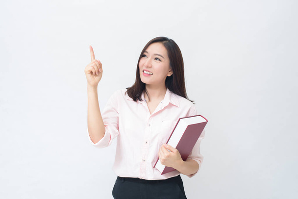 portrait of beautiful woman student in pink shirt is holding a book isolated over white background studio - Foto, afbeelding