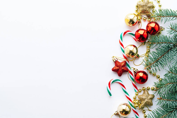 Christmas frame. Christmas balloons, garlands, red and gold decorations, Christmas candies and fir branches on a white background. Flat lay, top view, copy space. - Photo, Image