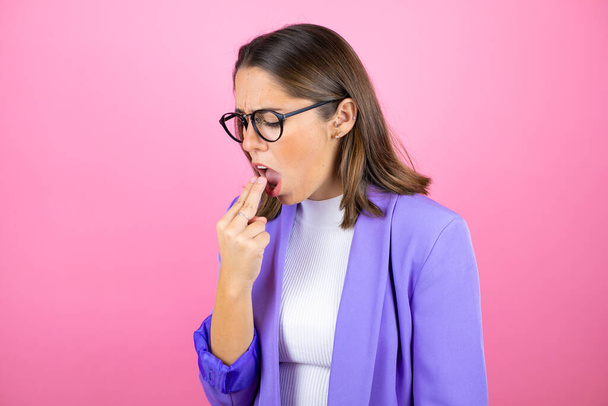 Young beautiful business woman over isolated pink background background disgusted with her hand inside her mouth - Photo, Image