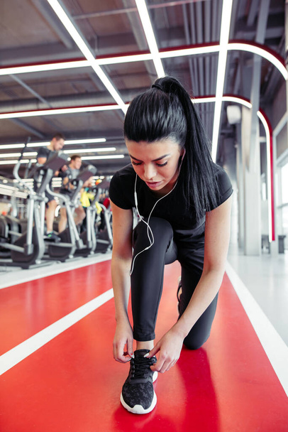 girl down to do shoelaces at fitness gym before running exercise workout - Photo, Image