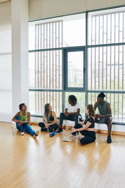 Багатоетнічна група танцюристів обговорює майбутній концерт після тренувань у танцювальному класі
 - Фото, зображення