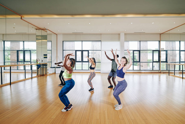 Groupe de jeunes qui aiment danser devant un grand miroir en studio - Photo, image
