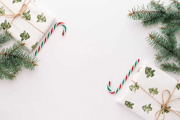 Christmas composition. Gifts, fir branches, red and green Christmas candies, decorations on a white background. The concept of Christmas, winter, New year. Flat layout, top view, copy space. - Fotografie, Obrázek