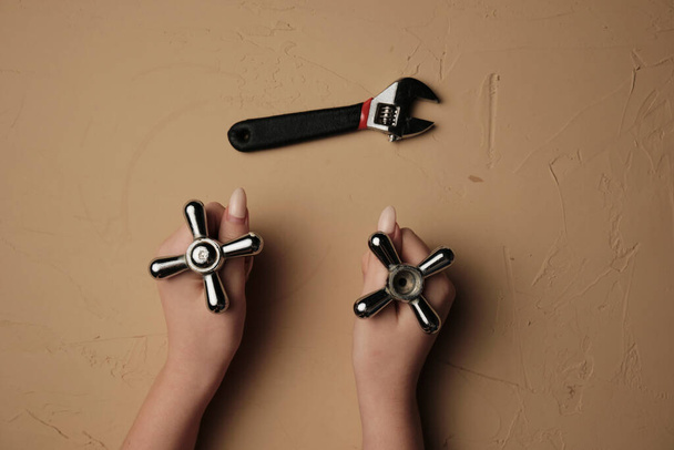 Une fille avec une clé. Outil pour la réparation de la plomberie avec leurs mains Clé gros plan dans une main de femme. - Photo, image