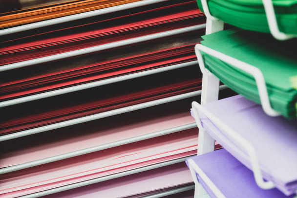 Stapels gekleurd papier in rood, roze, lila en groen. - Foto, afbeelding