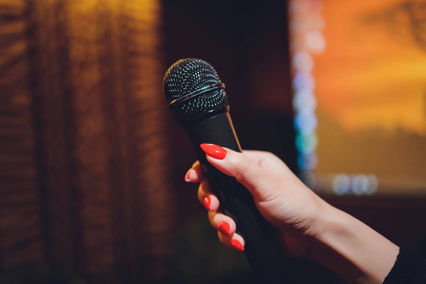 Microphone and female singer close up. Woman singing into a microphone, holding mic with hands. - Foto, imagen