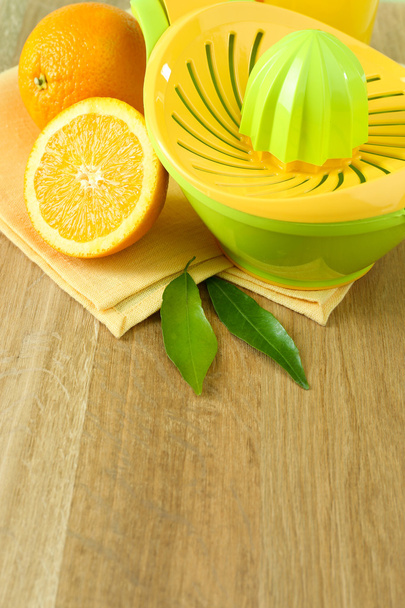 Citrus press and oranges on table on blue background - Фото, зображення