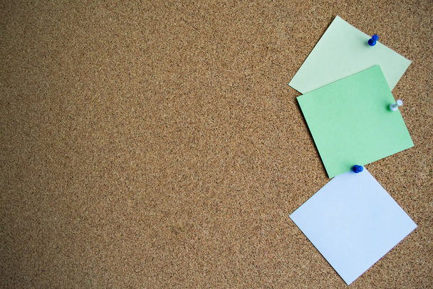 Trois notes de papier de couleur verte, blanche et jaune sur un panneau de liège, attaché avec une broche blanche. Espace de copie. - Photo, image