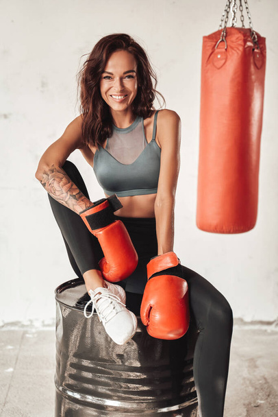 Female boxer sitting on barrel in training room - Photo, Image