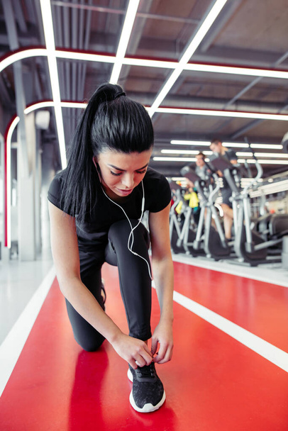 woman tying shoelaces at fitness gym before running on running track - Fotoğraf, Görsel