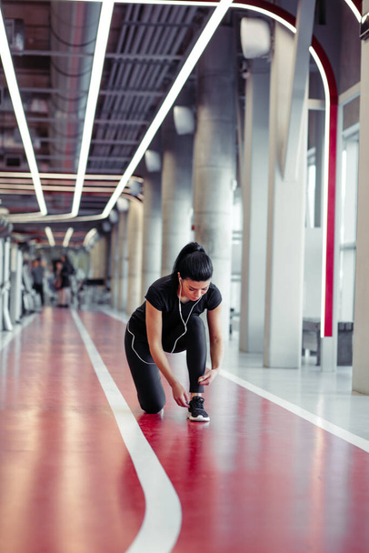 woman tying shoelaces at fitness gym before running on running track - Foto, Imagem