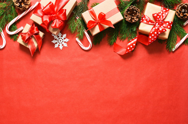Gift boxes with red ribbons and candy canes. Beautiful Christmas composition on a red background with fir. - Foto, Bild