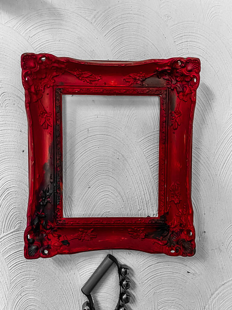View on isolated old red vintage empty picture frame on white wall (focus on frame) - Foto, Bild