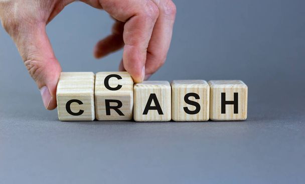 Symbol for selling stocks before a crisis. Hand turns a cube and changes the word crash to cash. Beautiful grey background, copy space. Business concept. - Photo, Image