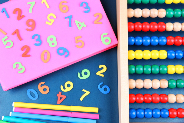 Números coloridos, ábaco, libros y marcadores en el fondo del escritorio de la escuela
 - Foto, imagen