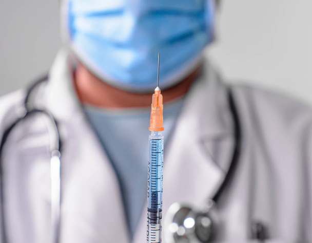 Doctor with mask holds syringe with vaccine - Valokuva, kuva