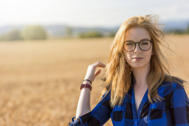 Portrait of cool young woman  posing in windy day in the corn field. Horizontally.  - 写真・画像