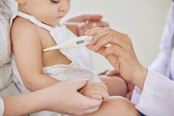 Image en gros plan du pédiatre vérifiant la température de la petite fille avec thermomètre électronique - Photo, image