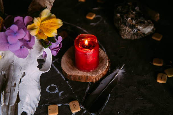 White goat scull with horns, flowers, open old book, candles on witch table. Occult, esoteric, divination and wicca concept. Halloween, Day of the dead concept - Fotoğraf, Görsel