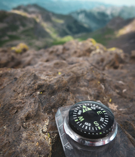 A close up of a compass on a rocky surface pointing north with mountains and valleys in the background in Switzerland - Photo, Image