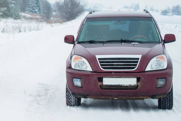 burgundy crossover standing on a snowy country road - Foto, Imagen