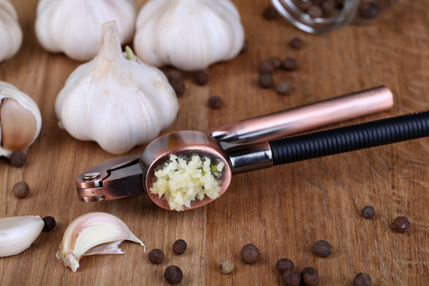 Garlic press on wooden background - Φωτογραφία, εικόνα