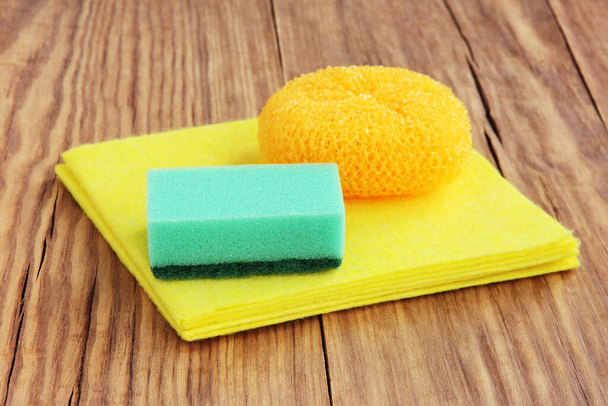 Cleaning sponge, brush scrubber and yellow micro fiber cloth on wooden background. Household concept. - Foto, immagini