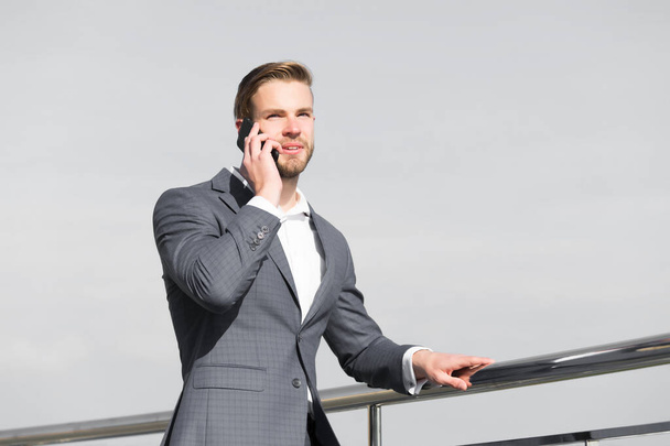 Man with smartphone on terrace on blue sky, business communication - Fotografie, Obrázek