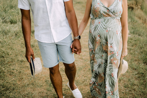 an interracial couple walking hand in hand through the forest - Photo, Image