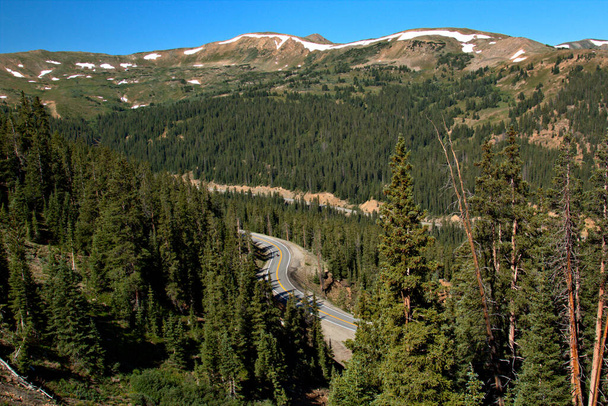 Draaiende snelweg door een bergpas met besneeuwde toppen - Foto, afbeelding