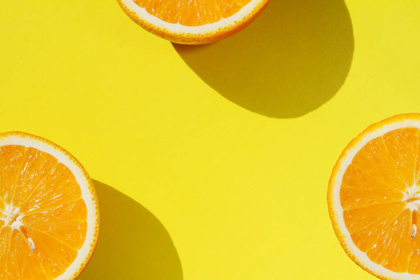 Helften rijpe sinaasappels op felgele achtergrond, bovenaanzicht met kopieerruimte - Foto, afbeelding