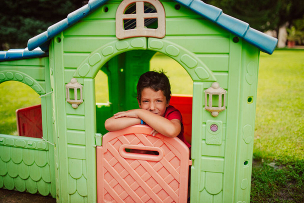 Портрет красивого кавказского мальчика в красочном доме в парке. День в природе - Фото, изображение