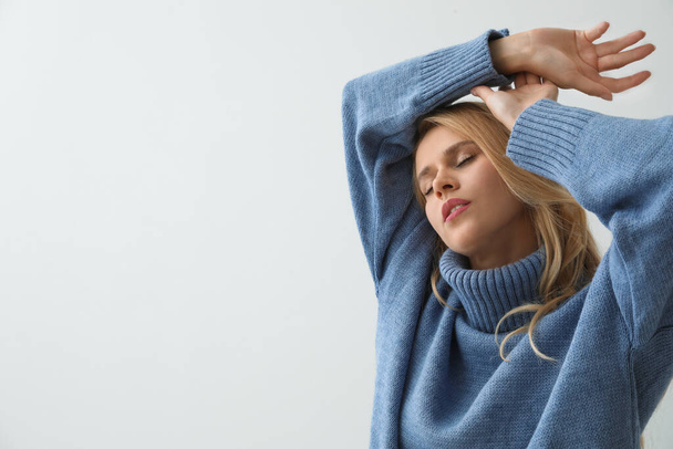 Beautiful young woman wearing warm blue sweater on light background. Space for text - Foto, afbeelding