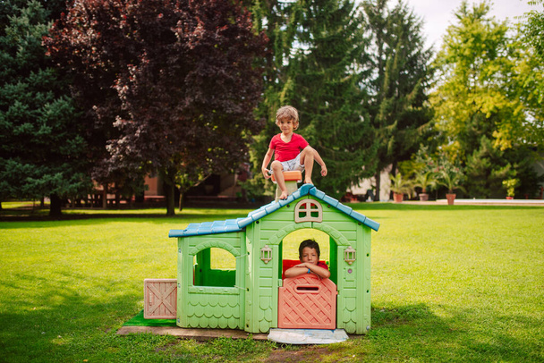 Beaux garçons caucasiens jouent dans une maison colorée dans le parc. Une journée dans la nature - Photo, image