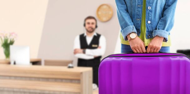 Woman with suitcase near receptionist in hotel, closeup view - Fotoğraf, Görsel