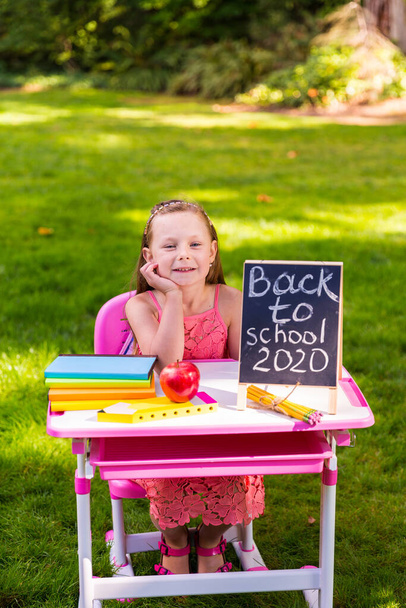 Школярка сидить за шкільним столом на вулиці в парку
 - Фото, зображення