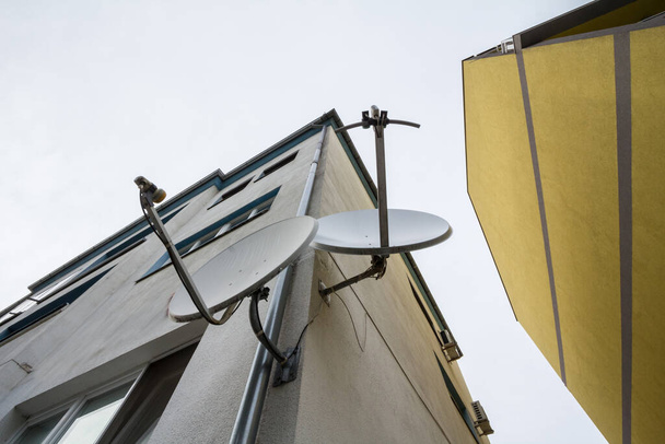 Zwei Satellitenschüsseln und Antennen auf dem Dach eines Wohnhauses. Diese werden für Kommunikation und Satellitenfernsehempfang verwendet - Foto, Bild