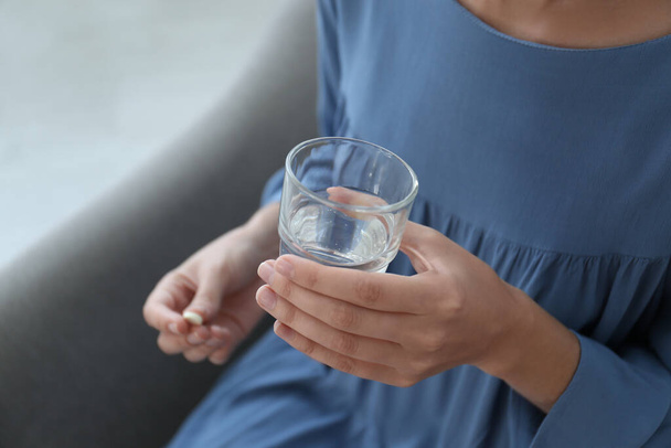 Woman holding glass of water and pill at home, closeup - Fotografie, Obrázek