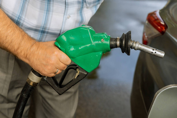 Автозаправщик на АЗС человек, закачивающий бензин в бензобак, заправляет бак - Фото, изображение