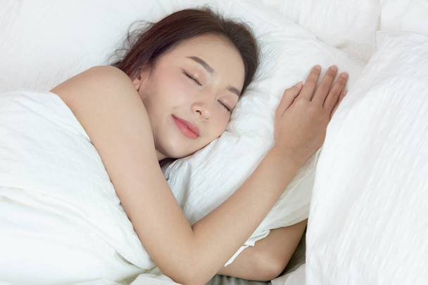 Ασιάτισσες κοιμούνται και γλυκό όνειρο σε λευκό κρεβάτι στην κρεβατοκάμαρα - Φωτογραφία, εικόνα
