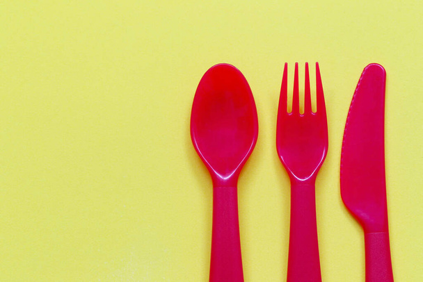 Cucchiaio rosso e forchetta su sfondo giallo e hanno spazio di copia per la progettazione nel vostro lavoro. - Foto, immagini