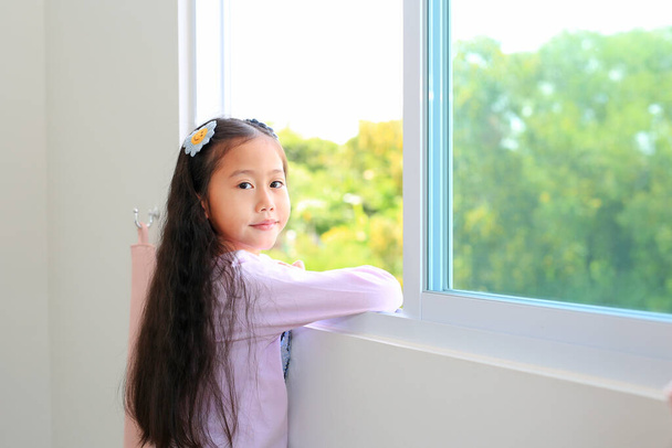 Beautiful asian little kid girl at home lying at window of house. - Foto, imagen