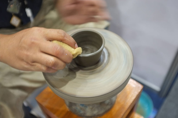Концепція керамічної майстерні. Чоловік кидає глиняну чашу на керамічне колесо
. - Фото, зображення