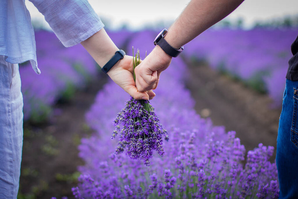 Het verliefde stel houdt elkaars hand vast in een lavendelveld. - Foto, afbeelding