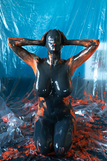 mujer desnuda rociada con pintura negra y naranja - Foto, imagen
