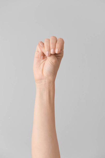 Hand showing letter M on grey background. Sign language alphabet - Foto, imagen