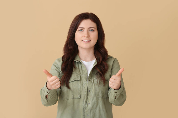 Young deaf mute woman using sign language on color background - Photo, Image