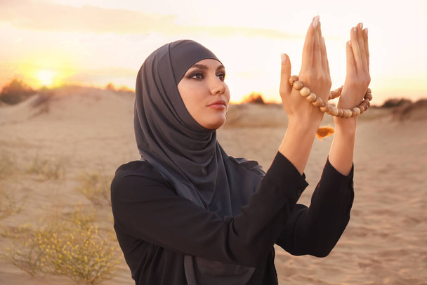 Beautiful Muslim woman praying in desert - Photo, Image
