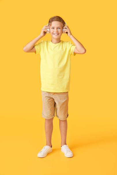 Little boy listening to music on color background - Фото, изображение