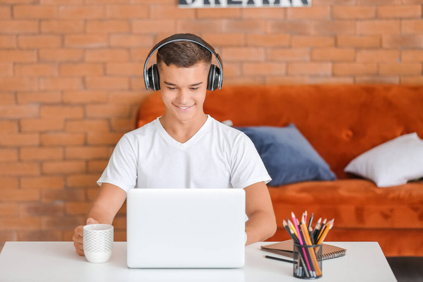 Tini fiú laptoppal zenét hallgat otthon - Fotó, kép